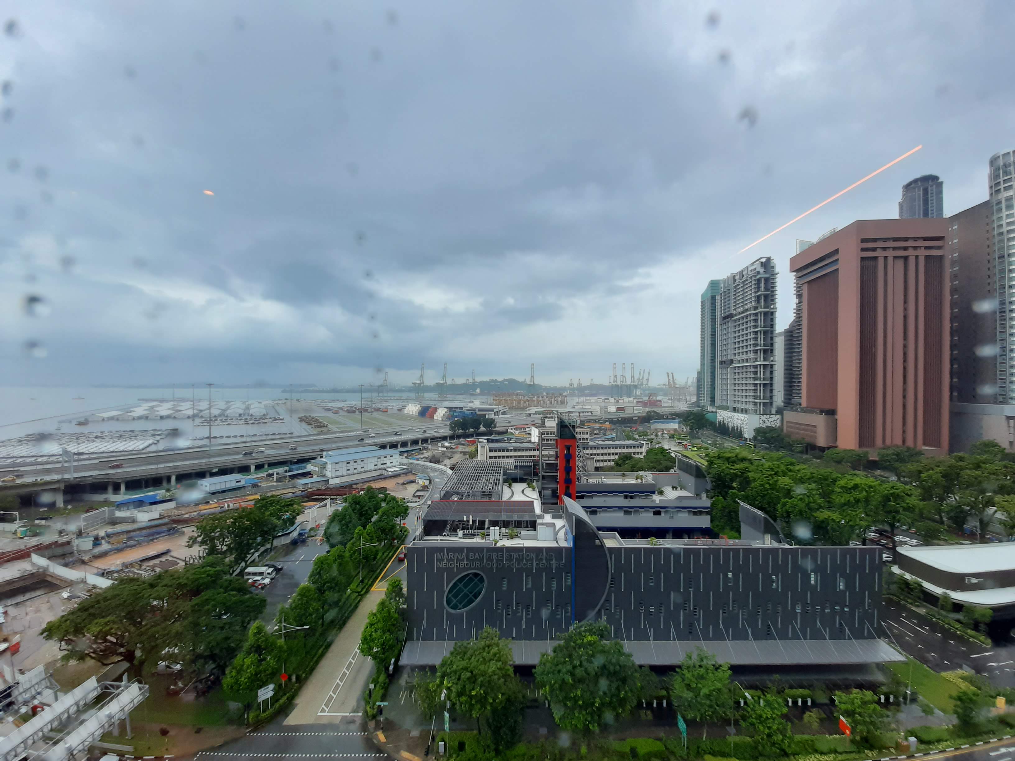 View from the window, Tanjong Pagar port terminal with cranes and containers and forested hills in the background.